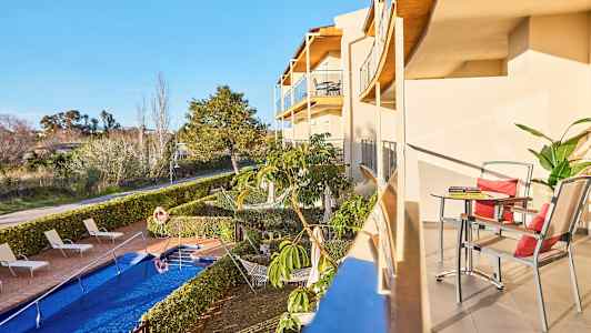 En altan med bord og stole samt udsigt over poolområdet og haven. (AI-genereret tekst)