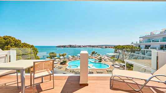 Hotelværelsesudsigt mod poolområde og hav. (AI-genereret tekst)