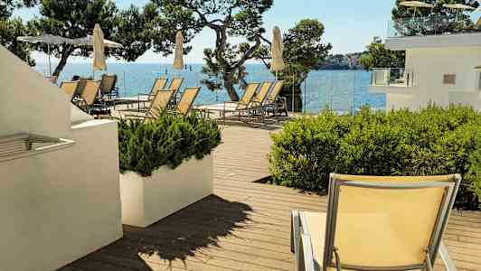 Liggestole og parasoller på en terrasse med havudsigt. (AI-genereret tekst)
