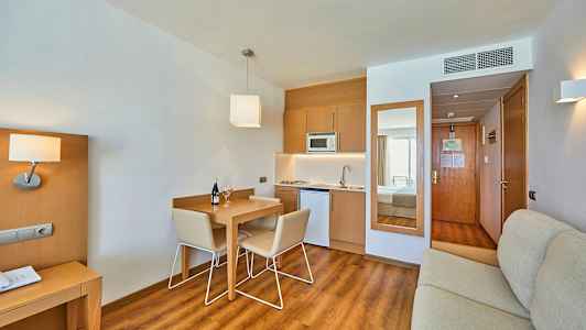 Et hotelværelse med køkkenområde og spisebord. (AI-genereret tekst)