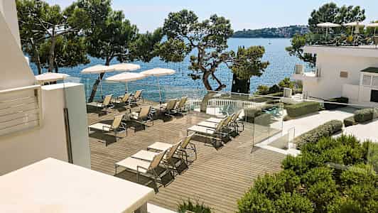 En solterrasse med liggestole og parasoller ved havet. (AI-genereret tekst)