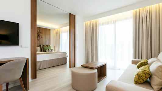 Lyst og indbydende hotelværelse med separat soveområde og opholdsområde. (AI-genereret tekst)