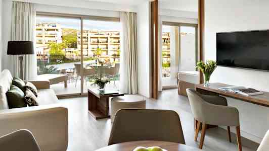 Moderne indrettet hotelsuite med siddeområde, bord og altan. (AI-genereret tekst)