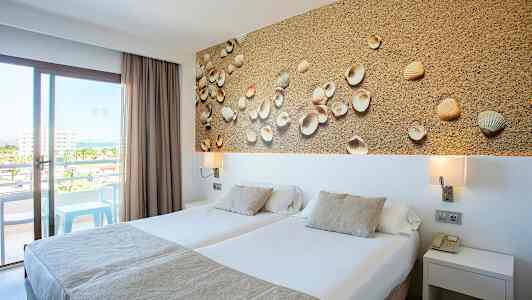 Hotelværelse med to enkeltsenge, dekorativt billede med skaller og balkon med udsigt. (AI-genereret tekst)