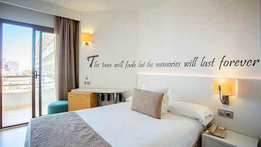 Hotelværelse med en dobbeltseng, skrivebord og altandør. (AI-genereret tekst)