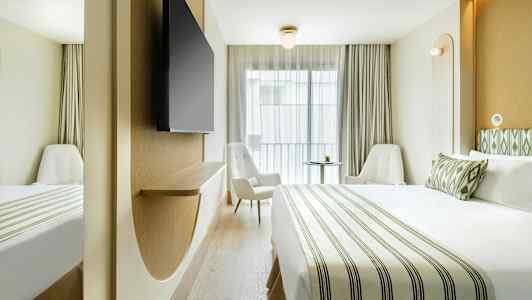 Et moderne hotelværelse med en stor seng, to stole og et vægmonteret TV. (AI-genereret tekst)