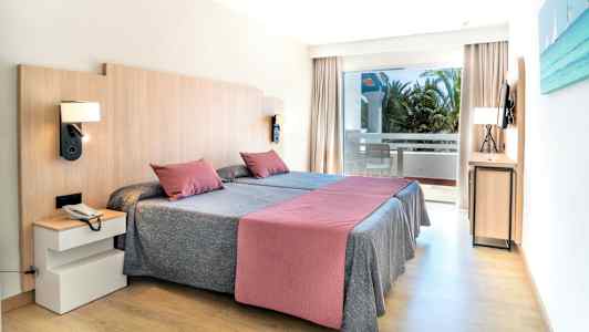 Et hotelværelse med to enkeltsenge, en balkon og moderne indretning. (AI-genereret tekst)