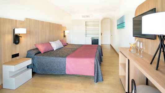 Et hotelværelse med to senge, en moderne indretning med trædetaljer, og et tv på væggen. (AI-genereret tekst)