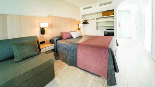 Et hotelværelse med en dobbeltseng, en sofa og en åben garderobe. (AI-genereret tekst)