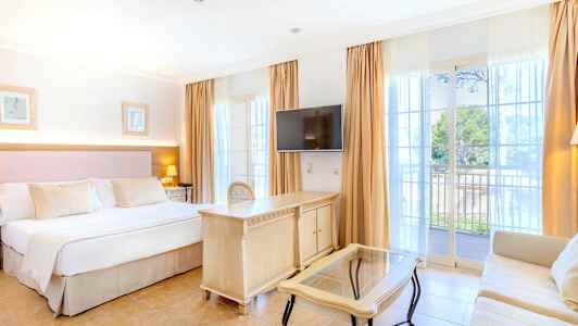 Hotelværelse med dobbeltseng, tv, skrivebord og sofa. Altan med udsigt. (AI-genereret tekst)