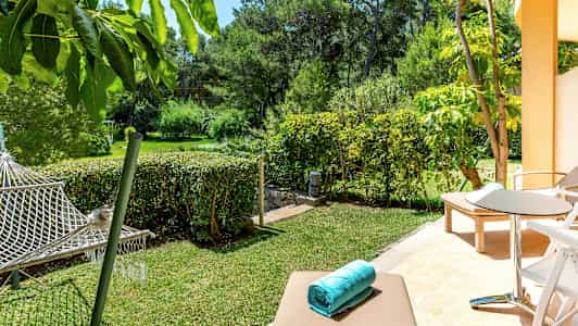 En terrasse med liggestole og siddeområde, udsigt til en have med hængekøje. (AI-genereret tekst)