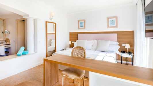 Lyst og rummeligt hotelværelse med dobbeltseng, skrivebord og stol. (AI-genereret tekst)