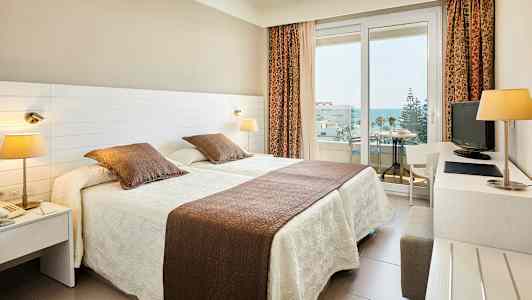 Hotelværelse med to enkeltsenge og balkon. (AI-genereret tekst)