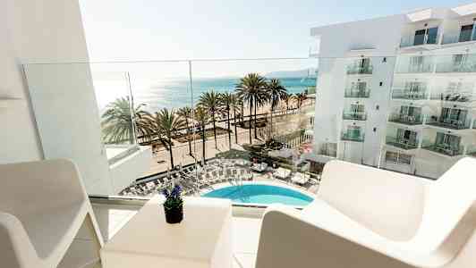 Udsigt fra en altan mod en pool, palmer og havet. (AI-genereret tekst)