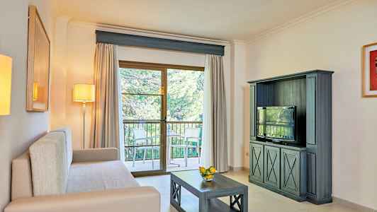 Stue med lys sofa, tv-møbel, sofabord og altandør med udsigt. (AI-genereret tekst)