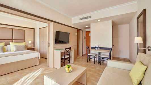 Et hotelværelse med seng, siddeområde og spisebord. (AI-genereret tekst)