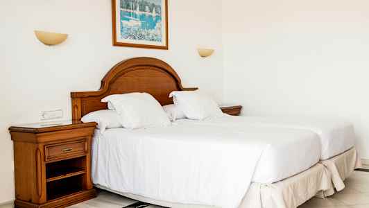 Et soveværelse med to enkeltsenge, en træ-topgavl og et natbord. (AI-genereret tekst)