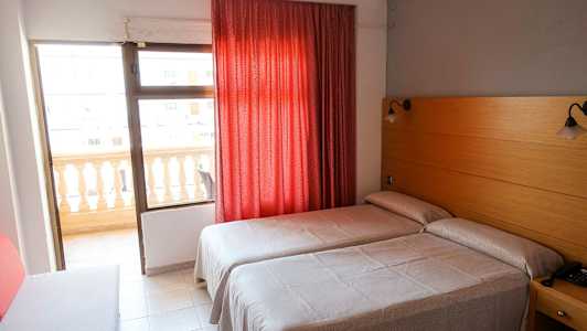 Hotelværelse med to enkeltsenge, rød gardin og altan. (AI-genereret tekst)