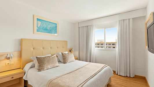 Et hotelværelse med en dobbeltseng, vindue og lyse gardiner. (AI-genereret tekst)