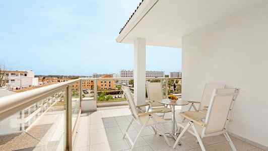 En altan med bord og stole samt udsigt over de omkringliggende bygninger. (AI-genereret tekst)