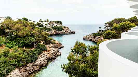 Udsigt over en bugt med klart vand, grønne træer og hvide bygninger. (AI-genereret tekst)