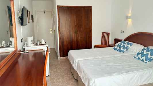 Soveværelse med to enkeltsenge, et klædeskab og trømøbler. (AI-genereret tekst)