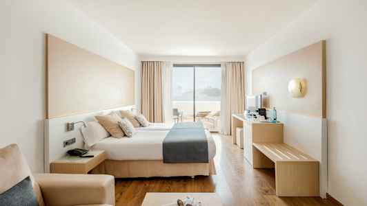 Moderne hotelværelse med dobbeltseng og udsigt til terrasse og hav. (AI-genereret tekst)