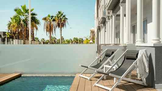 Liggestole ved en lille pool med udsigt til palmer. (AI-genereret tekst)