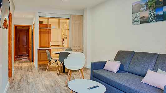 En stue med en sofa, et sofabord og en spiseplads tæt på et køkken. (AI-genereret tekst)