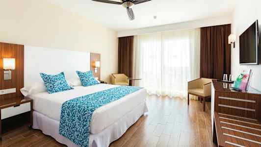 Hotelværelse med en dobbeltseng, blåt tekstil og en moderne indretning. (AI-genereret tekst)