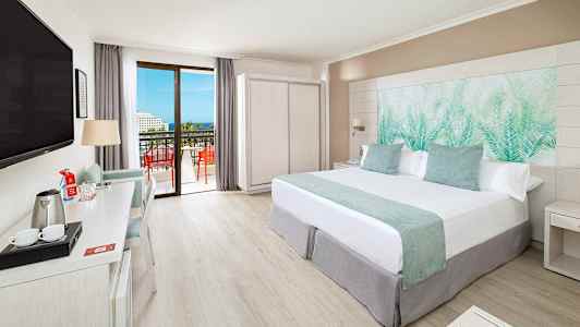 Moderne hotelværelse med dobbeltseng, skrivebord, TV og altan med udsigt. (AI-genereret tekst)