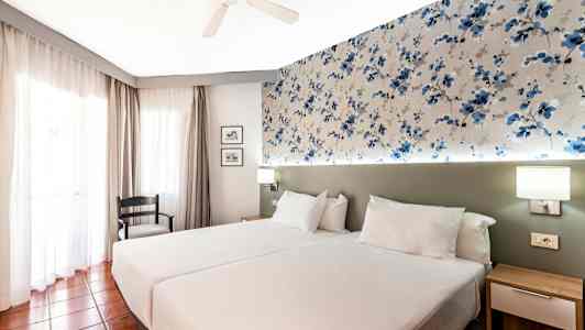 Et hotelværelse med to enkeltsenge og mønstret vægdekoration. (AI-genereret tekst)