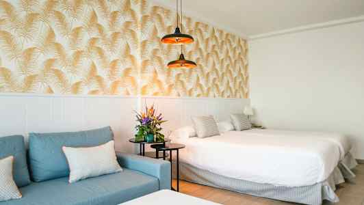 Hotelværelse med blå sofa, dobbeltseng og dekorativ tapet. (AI-genereret tekst)