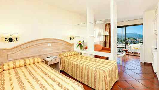 Et hotelværelse med to enkeltsenge, en siddegruppe og altan. (AI-genereret tekst)