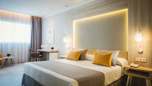 Et moderne hotelværelse med dobbeltseng, skrivebord og siddeområde. (AI-genereret tekst)