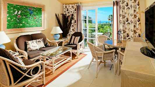 En dagligstue med rottingmøbler, et glasbord og et farverigt billede på væggen. (AI-genereret tekst)