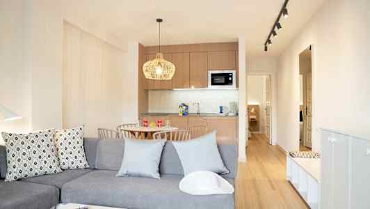 Moderne indrettet stue med køkkenafdeling og spisebord. (AI-genereret tekst)