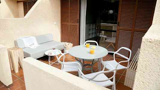 En terrasse med en grå sofa, et rundt bord og stole. (AI-genereret tekst)