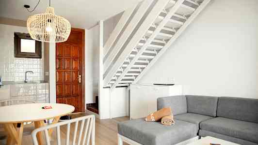 Indendørs udsigt med stue, køkkenområde og trapper i hvidt og træinteriør. (AI-genereret tekst)