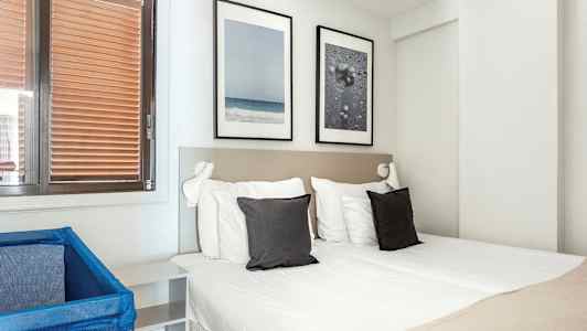 Et hotelværelse med en dobbeltseng, to puder og dekorationer på væggen. (AI-genereret tekst)