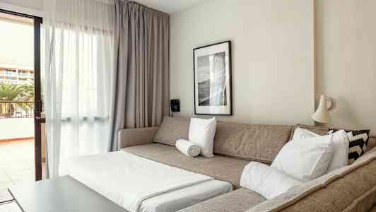 Et opholdsrum med en sovesofa, et sofabord og en udgang til altan. (AI-genereret tekst)