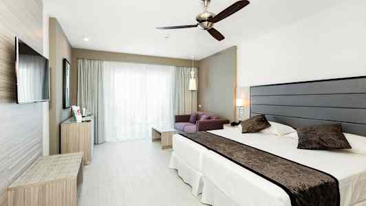 Billede af et hotelværelse med en seng, en sofa og et tv. (AI-genereret tekst)