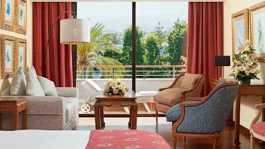 Et hotelværelse med møbler, blomster og udsigt til en frodig altan. (AI-genereret tekst)