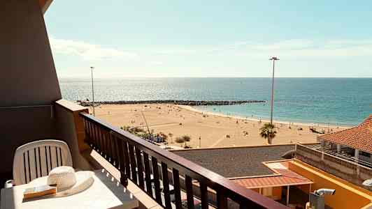 En balkon med udsigt over en sandstrand og havet. (AI-genereret tekst)