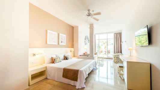 Lyst hotelværelse med dobbeltseng og udsigt til en terrasse. (AI-genereret tekst)