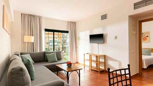 Billede af en stue med en grå sofa, bord og et TV på væggen. (AI-genereret tekst)