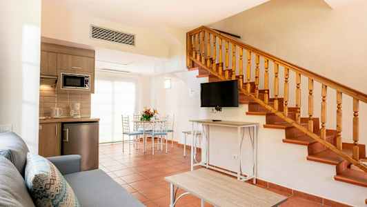 En stue med trappe, køkkenudstyr og spiseområde. (AI-genereret tekst)