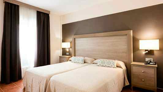 Et soveværelse med to enkeltsenge, en fælles sengegavl og mørke gardiner ved et vindue. (AI-genereret tekst)