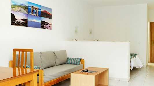 En stue med en sofa og et sofabord, samt en åbning mod et soveværelse. (AI-genereret tekst)