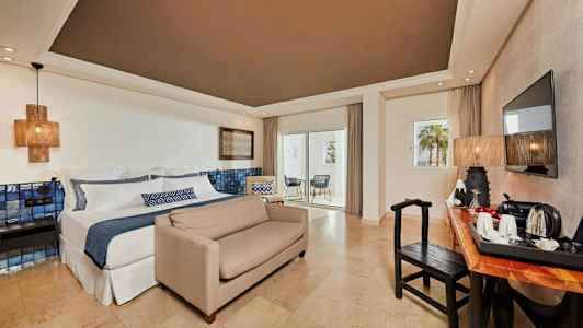 Hotelværelse med dobbeltseng, sofa, skrivebord, tv og altan. (AI-genereret tekst)